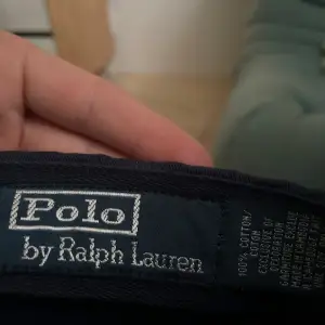 Säljer en snygg mörkblå keps från Polo Ralph Lauren. Kepsen har den klassiska broderade loggan framtill och 'POLO' broderat baktill. Justerbar rem för perfekt passform. Perfekt för både vardag och sportiga aktiviteter!