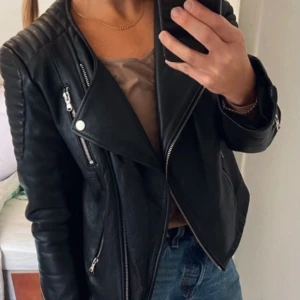 Biker jacka/skinnjacka  - Skinnjacka i MC modell från h&m studio. Tidlös använd fåtal gånger, därav fortfarande ganska hård i skinnet. Storlek 42,  mkt liten i storleken och skulle beskriva den som S/M/38, beroende på hur man vill ha passformen. Jag är ca 36/38, 157cm.