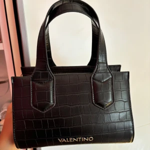Valentino väska - Svart valentino väska. Detta är en Mario Valentino väska inte en Valentino Garavani väska ❗️Ett längre band medföljer. Använt en del men fortfarande bra skick finns lite defekter som jag visat på sista bilderna 💕