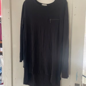 Svart långärmad tröja från Xside - Säljer en svart långärmad tröja från Xside i storlek XL. Tröjan har en enkel design med en liten dragkedja på bröstet. Perfekt för en avslappnad stil och passar bra till både jeans och leggings.