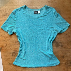 Turkos kortärmad topp från Urban Outfitters - Säljer en snygg blå toppens glitter i. Den är kortärmad och har en rund halsringning. Perfekt som ett basplagg i garderoben.