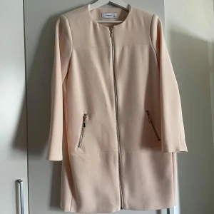 Reserved ljusrosa ny jacka. Storlek 34 -  En ljusrosa jacka med dragkedja framtill och fickor med dragkedja på sidorna. Jackan har en rak passform och är tillverkad i ett tunt, lätt material. Aldrig använd, helt ny. Lapparna sitter inte kvar.  🚭Djurfritt och rökfritt hem 