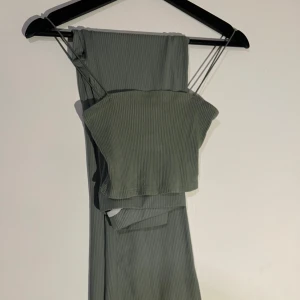 Grön ribbad tubtopp och byxor - Snygg grön ribbad tubtopp med smala axelband och matchande byxor. Perfekt för en stilren och bekväm look. Toppen är croppad och byxorna har en avslappnad passform.