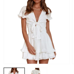 Vit kortklänning med volanger - Charmig vit kortklänning med volanger och knytning framtill. Klänningen har korta ärmar och en v-ringad design som ger en feminin touch. Perfekt för somriga dagar och studenten. Tyvärr är den lite för liten för mig. Skriv om man vill ha fler bilder 😊