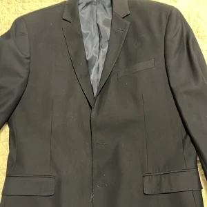 Mörkblå kavaj från Strömberg - Elegant svart kavaj från Strömberg med en skräddarsydd passform. Kavajen har klassiska slag och är perfekt för formella tillfällen. Den är tillverkad i ett stilrent material och har en diskret ficka på bröstet.