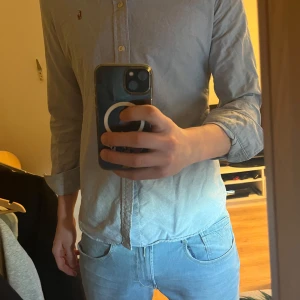 Blå skjorta från Ralph Lauren - Snygg blå skjorta från Ralph Lauren med klassisk krage och knappar framtill. Skjortan har långa ärmar och en liten broderad logotyp på bröstet. Perfekt för en stilren look.