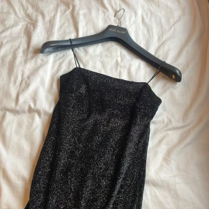 Svart glittrig klänning  - Snygg svart glittrig klänning med smala axelband, perfekt för en festlig julkväll! Klänningen har en elegant och stilren design, endast använd en gång. 