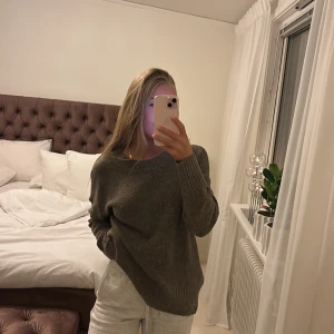 Grå stickad tröja - Mysig grå stickad tröja med rund hals och långa ärmar. Perfekt för kyliga dagar och enkel att matcha med olika outfits.