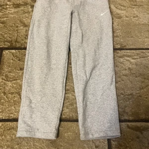 Grå mjukisbyxor från Nike - Säljer ett par grå mjukisbyxor från Nike i storlek L. Byxorna har en enkel design med en liten Nike-logga på benet. Perfekta för en avslappnad stil.