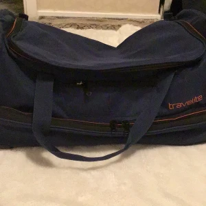 Mörk blå resväska från Travelite - Säljer en praktisk mörk  resväska från Travelite med hjul och utdragbart handtag. Väskan har en stor öppning med dragkedja och flera fack för enkel packning. Perfekt för resor och äventyr.
