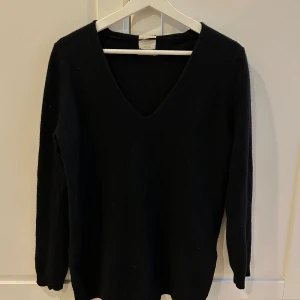 Svart 100% kashmirtröja med v-ringning - Elegant svart 100% kashmirtröja med v-ringning och långa ärmar. Perfekt för kyligare dagar och ger en stilren look.