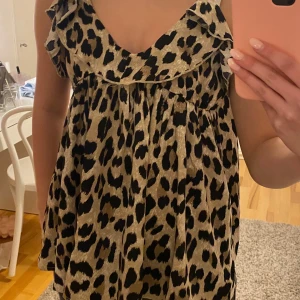 Leopardmönstrad ärmlös topp - Snygg leopardmönstrad topp med volangdetaljer och smala axelband. Perfekt för en trendig look.