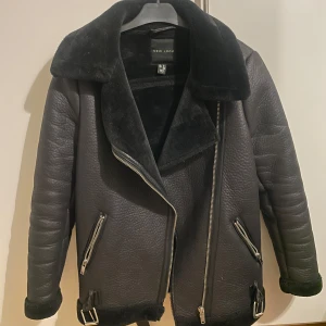 Svart jacka från New Look - Snygg svart jacka från New Look med fuskpälsdetaljer och dragkedjor. Perfekt för kyligare dagar med sin stilrena design och bekväma passform. Perfekt även till utekvällar!!