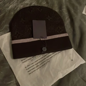 Brun mössa med knappdetalj - Snygg brun mössa med en dekorativ knappdetalj framtill. Mössan har en bred kant i en ljusare nyans som ger en fin kontrast. Perfekt för kyliga dagar. 3 st inne. Skriv dm för bilder 