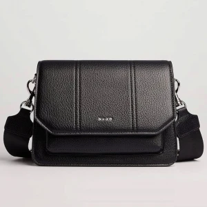 Svart axelväska från NA-KD - Snygg svart axelväska från NA-KD i skinnimitation med textur. Väskan har en justerbar axelrem och en stilren design med silverdetaljer. Perfekt för att bära dina nödvändigheter med stil. Köpt för 549 men slutsåld på hemsidan, få användningar så bra skick. 