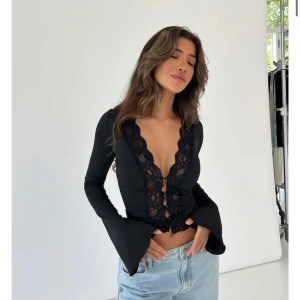 Svart långärmad topp med spetsdetaljer från Venderbys - Elegant svart topp från Venderbys med långa ärmar och vacker spetsdetalj. Toppen har knappar framtill och en figurnära passform.  Den var otroligt fin men tyvärr lite liten på mig och det är försent att skicka tillbaka den nu. Helt oanvänd 