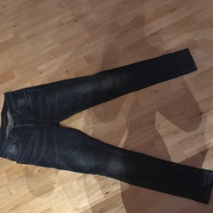 Mörkblå jeans från Nudie Jeans - Snygga mörkblå jeans från Nudie Jeans med en klassisk femficksdesign. De har en knappgylf och subtila slitningar för en trendig look. Perfekta för en stilren vardagsoutfit.