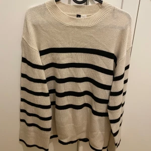 Randig tröja från H&M Divided - Säljer en stilren randig tröja från H&M Divided i beige och svart. Tröjan har långa ärmar och en rund halsringning, perfekt för en avslappnad look. Passar bra till både jeans och kjol. Vida armar.