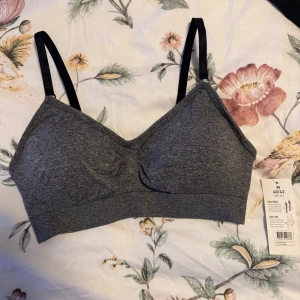 Grå sport-bh från In Motion - Säljer en grå sport-bh från In Motion i storlek M (40/42). Den har justerbara svarta axelband och är tillverkad i ett snabbtorkande och andningsbart material, perfekt för träning. Bekväm och stilren design.