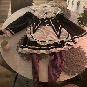 Maid dress/cosplay dress - En maid dress i superfint skick förutom en fläck på en av ärmarna som man kan välja att inte ha om man vill som borde gå bort i tvätten eller med någon speciell slags borttagning eller blekning om de behövs på den/dom! Superfint skick annars och har superfina tillbehör till som ärmarna som tillbehör och hals grejen/dekorationen som tillbehör! Knappt använd endast en halloween för länge sedan när jag var mindre!