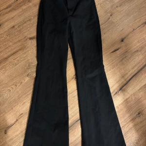 Svarta byxor från Zara - Snygga svarta byxor från Zara med en elegant bootcut-stil. Perfekta för en stilren look och passar till många olika tillfällen. Byxorna har en hög midja som ger en smickrande passform. Perfekt julklapp. 