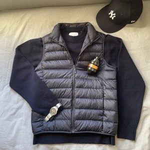 Snygg Svart dunväst från Uniqlo - Säljer en riktigt snygg väst från uniqlo i toppen skick. Inge defekter eller fläckar finns på den. Perfekt för kallare vårdagar eller sommarkvällar. Bara att höra av sig om man har några frågor🤗  ‼️ inget annat på bilden ingår förutom västen utan är bara för prydnad 