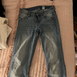 Blå bootcut jeans - Säljer ett par snygga blå bootcut jeans med låg midja. Perfekta för en avslappnad stil. De har klassisk femficksdesign och knappgylf.