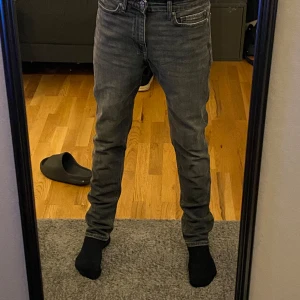 Grå jeans  - W 30 L32 Snygga grå jeansbyxor med en klassisk design. De har en slim passform och är perfekta för en avslappnad stil. Byxorna har en dragkedja och knappar framtill. Slim fit! (Oanvända)