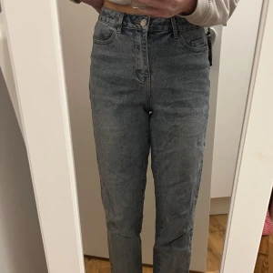 Blå jeans från Vila - Snygga blå jeans från Vila med hög midja och klassisk femficksdesign. Perfekta för en avslappnad stil med en tight passform som framhäver figuren. Tillverkade i ett bekvämt denimtyg.