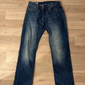 Levis 501 jeans - Klassiska Levis 501 jeans i blå denim. De har en rak passform och är midwaist. Perfekta för en avslappnad stil med knappgylf och femficksdesign.
