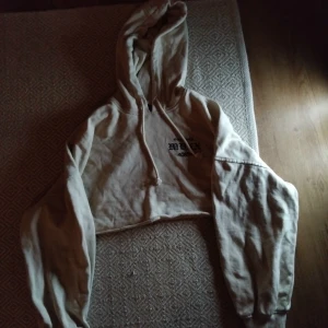 Beige croppad hoodie med tryck - Säljer en beige croppad hoodie med tryck på både framsidan och baksidan. Hoodien har en stor luva och långa ärmar, perfekt för en avslappnad stil. Passar bra till jeans eller leggings. kontakta mig vid frågor om mer bilder, mått, pris osv🥰