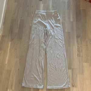 Beige vida byxor - Säljer ett par superbekväma och stilrena beige mysbyxor. De är högmidjade med ett resor och har en loose passform med vida ben. Materialet känns mjukt och skönt mot huden.