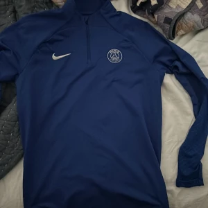  Paris Saint-Germain Träningströja Dri-FIT Strike Drill - Blå/Vit  - En blå/vit Paris Saint-Germain träningströja i storlek M. Oanvänd och köptes för 450 på rea men säljer tröjan för 350  kr. Som vanligt fraktar ej, däremot ja till att mötas upp om inte för långt så kan den hämtas 