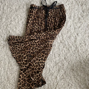 Leopardmönstrad kjol med knytband - Säljer en supercool leopardmönstrad långkjol med ett snyggt svart knytband i midjan. Kjolen har ett härligt flow och är perfekt för både fest och vardag. Den är i nyskick och redo att rocka din garderob! 🐆✨