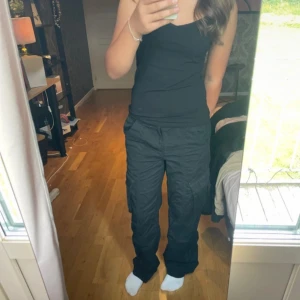 Svarta cargo pants - Snygga svarta cargo pants ifrån H&M! Storlek 34 men skulle säga passar 36 också eftersom den har resår i midjan. 
