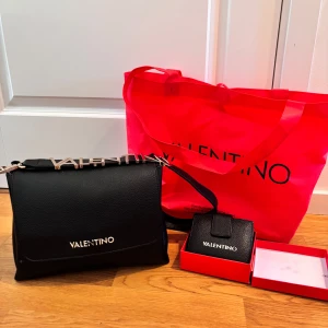 Svart handväska och plånbok från Valentino - Säljer min fina väska från Valentino tillsammans med matchande plånbok🫶🏻 Väskan är i mycket bra skick men har några små defekter som man ser på bilderna💕 Båda har köpts från zalando, alltså är de älta❤️ Nypris för båda tillsammas var 1500kr