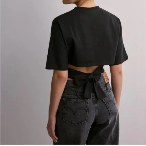 Nelly topp - Säljer denna open black Tie tee topp från Nelly då den tyvärr inte kommer till användning 