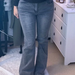 Grå jeans med broderade detaljer - Säljer ett par snygga grå jeans med broderade detaljer på bakfickorna. De har en flared passform. Perfekta för både vardag och fest.