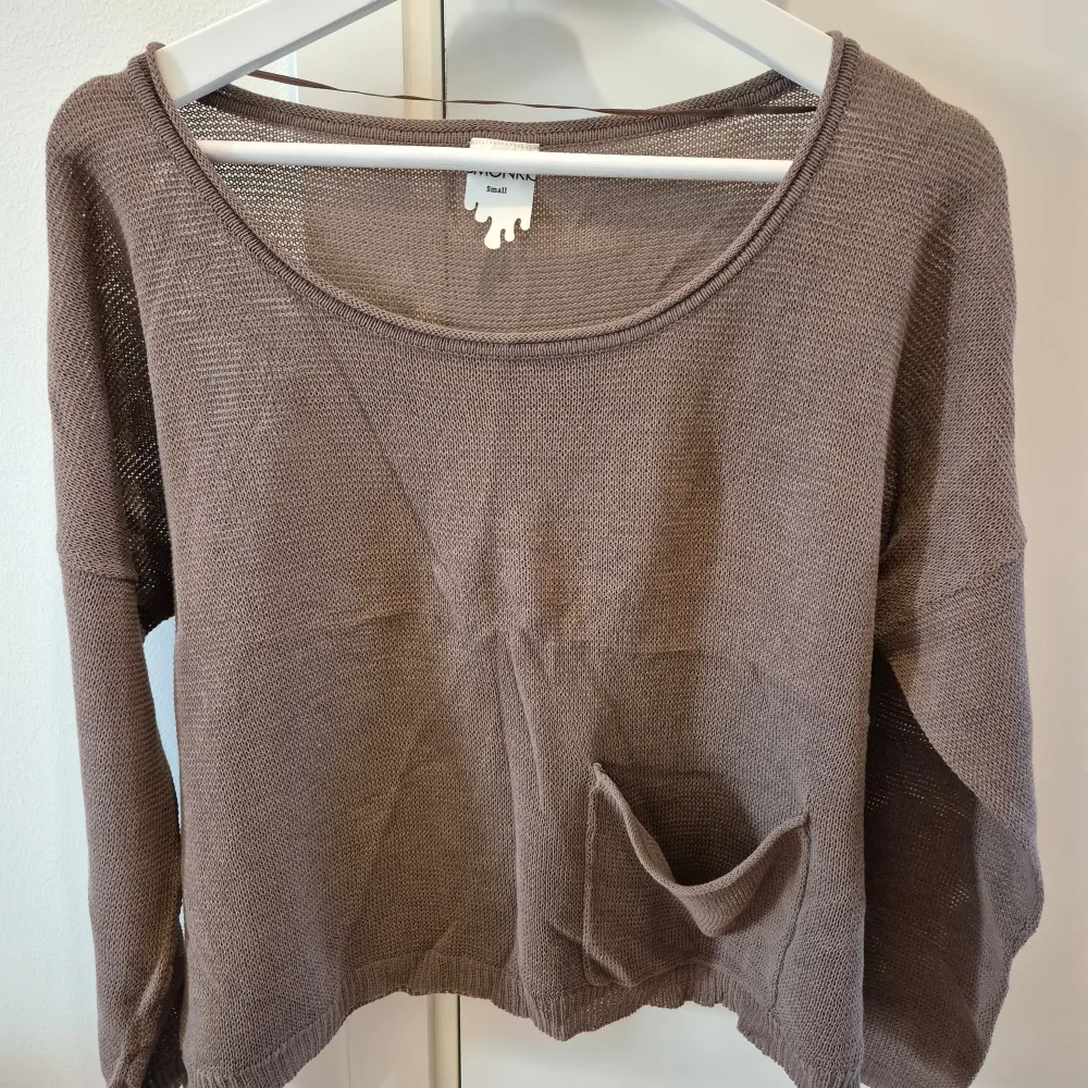 Oversized tröja med en ficka på framsidan från Monki. Lös modell och tunn material. Skön och bekväm. Storlek S. 100% bomull. Khaki färgad.. Neuletakit & Villapaidat.