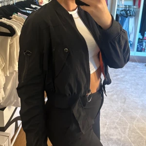 Bomberjacka - Kort bomberjacka med fina detaljer fram och på ena armen. Den har även en dragkedja bak som går att öppna helt. Vet inte varifrån den är köpt💕står att det är stl L, men vill man att den ska vara pösig skulle jag säga M