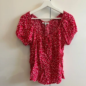 Röd blommig blus - Röd blommig blus från chiquelle. Sitter en säkerhetsnål bak då den varit för stor för mig annars. Köptes för några år sedan men knappt använd. 