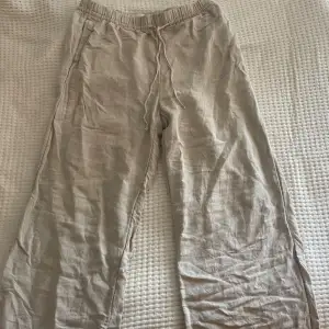 Säljer ett par bekväma och stilrena beige linnebyxor från H&M. De har en elastisk midja med snörning för extra komfort. Perfekta för en avslappnad sommarlook!