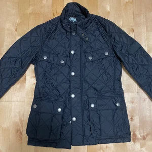 Barbour Field jacka - Säljer denna stilrena field jackan pga har ingen användning av den. Skick 9,5/10 inga defekter. Storlek XS passar 170 cm runt omkring. Färg: svart. Pris kan självklart diskuteras.💯💯💯