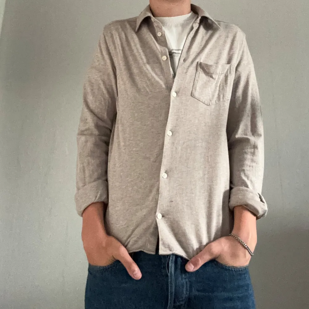 Säljer en stilren beige skjorta i mjukt bomullsmaterial. Riktigt det skjorta från J. Lindeberg. Modellen är 180cm och skjortan är lite för liten. Storleken på skjortan är S men passar även Xs. Skjortor.