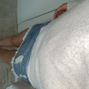 Jeanskjol med slitningar - Säljer en snygg jeanskjol med slitningar. Den är kort och har en fräsch, avslappnad stil. Perfekt för sommardagar eller en avslappnad utekväll. Kjolen har en klassisk blå jeansfärg och är gjord i ett bekvämt material.