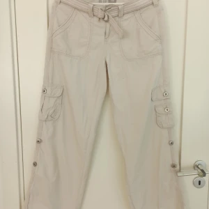 Beige cargobyxor från F&F Blue - Säljer ett par beige cargobyxor från F&F Blue i storlek 38. Byxorna har flera fickor med knappar och ett bälte i midjan. Perfekta för en avslappnad och bekväm stil. De är i bra skick och redo för en ny ägare! Enda defekten finns på näst sista bilden🌟