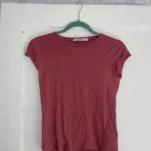 Rosa t-shirt från NA-KD - Säljer en söt rosa t-shirt från NA-KD i storlek XXS. Den är kortärmad och perfekt för sommardagar. Materialet känns mjukt och bekvämt, och den har en enkel och stilren design.