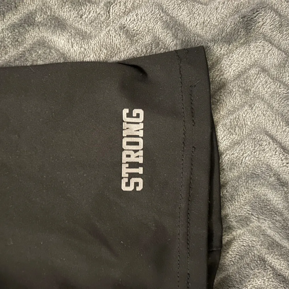 Säljer ett par svarta träningsshorts från märket Strong! Stretchigt och bekvämt material. Shortsen är lite längre i benen🌟. Sportswear.