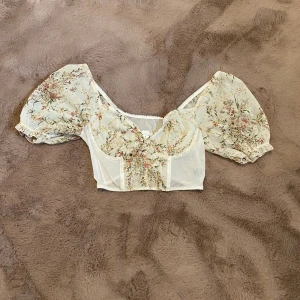 Blommig topp - Köpt secondhand och använt den ca 3 gånger och har en fläck på ryggen men annars är det bra skick på den! Säljer pga den har för liten byst för mig.