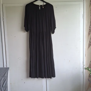 Svart långklänning från Soya Concept - Säljer en elegant svart långklänning från Soya Concept. Klänningen har en lös passform och är tillverkad i ett mjukt och bekvämt material. Den har trekvartsärmar och en rund halsringning. Perfekt för både vardag och fest!